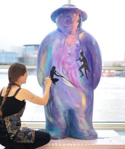 Artist Lois Cordelia painting a Snowman sculpture