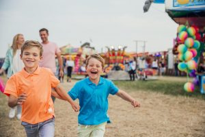 Happy children running ahead of their parents at a fun-fair